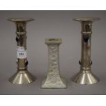 A pair of candlesticks and another. The former 16.5 cm high.