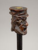 An ebony walking stick with carved wooden double head handle. 86 cm long.