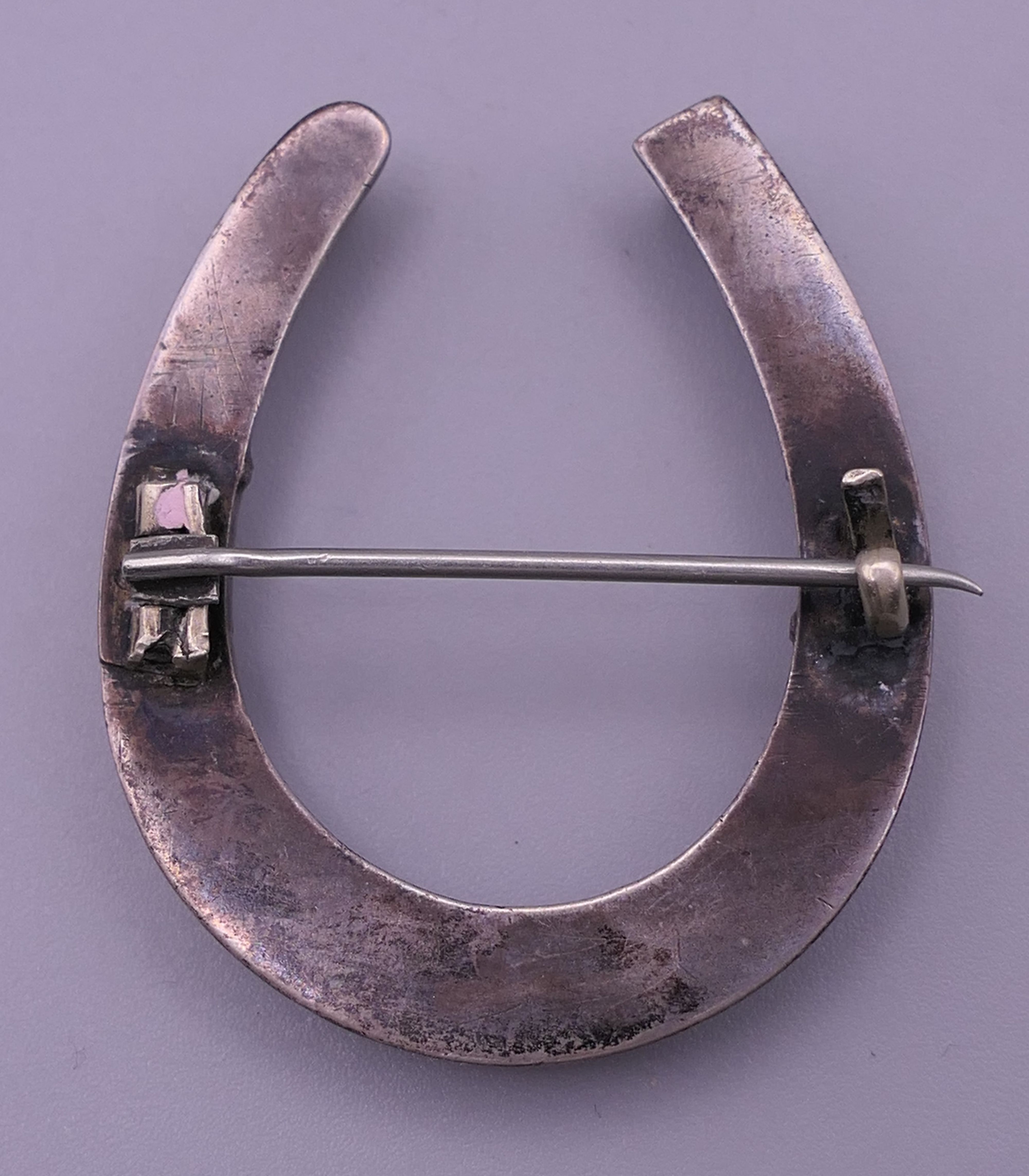 A silver locket, a white metal (silver) horseshoe brooch and a butterfly brooch. - Image 9 of 9