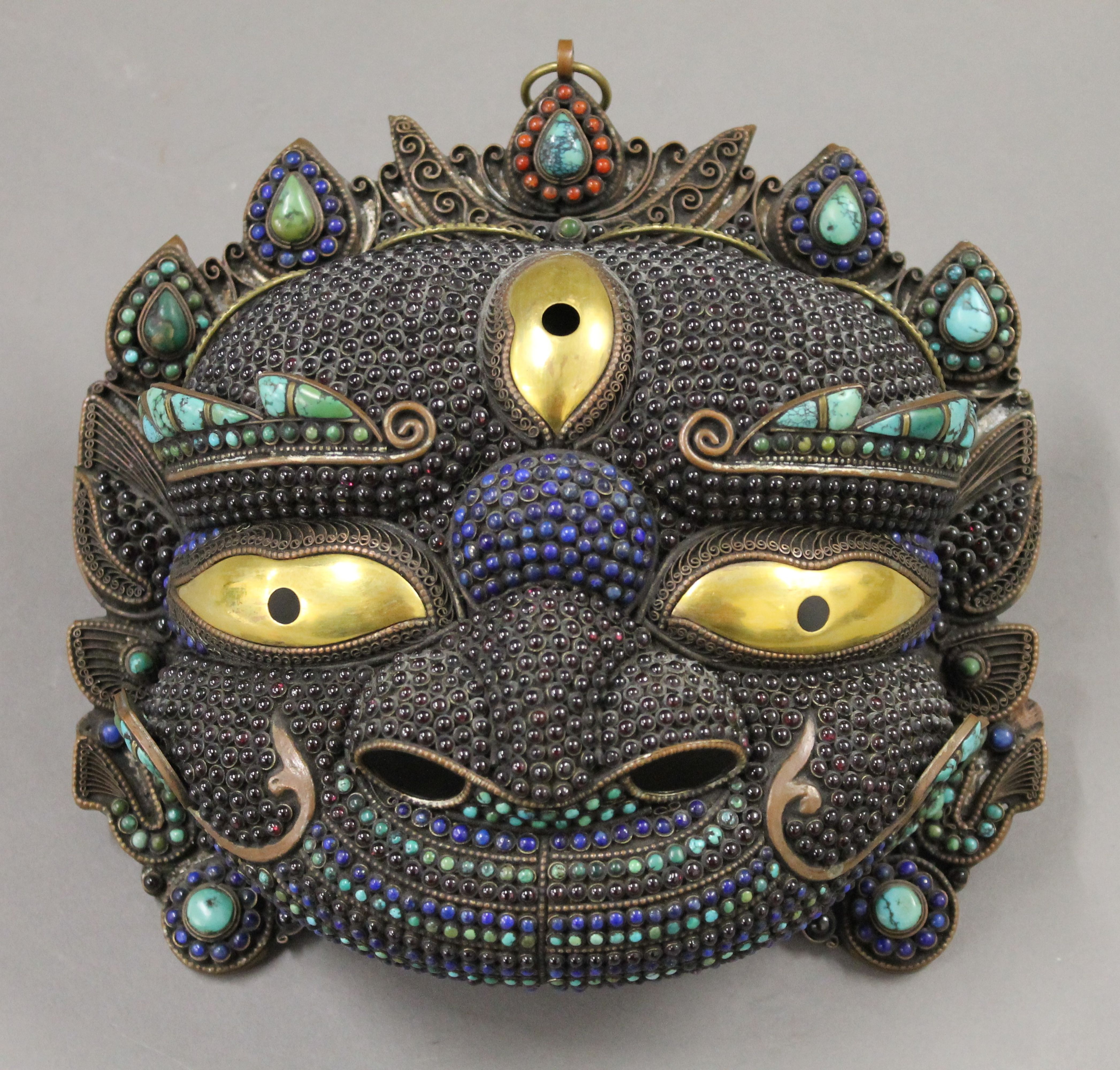 A Tibetan cabochon set copper and brass mask. 23 cm wide.
