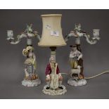 A pair of Continental porcelain figural candelabra and a table lamp. The former each 29 cm high.