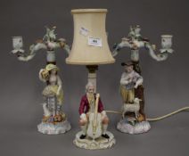 A pair of Continental porcelain figural candelabra and a table lamp. The former each 29 cm high.