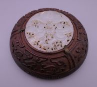 A Chinese carved celadon jade roundel mounted in a carved wooden frame. The roundel 6 cm diameter.