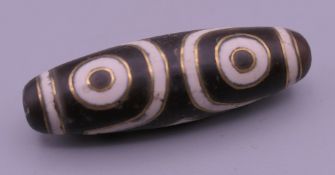 A Tibetan gold inlaid dzi bead. 3.75 cm long.