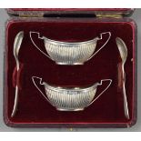 A cased pair of silver salts with one silver spoon and one plated spoon. 36.4 grammes.
