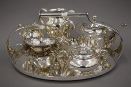 A three-piece silver plated tea set and a three-piece porcelain and silver overlaid tea set and an