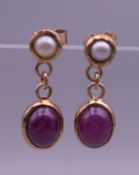 A pair of 9 ct gold cabochon ruby and pearl earrings. 2 cm high.