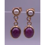 A pair of 9 ct gold cabochon ruby and pearl earrings. 2 cm high.