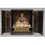 A Japanese deity in a black lacquered case. The case 20 cm high.