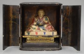 A Japanese deity in a black lacquered case. The case 20 cm high.