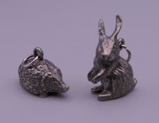 Two white metal pendants, one of a hare and the other of a hedgehog. The former 2.75 cm high.
