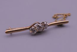 A 9 ct gold three stone diamond bar brooch. 4.5 cm long. 3.7 grammes total weight.