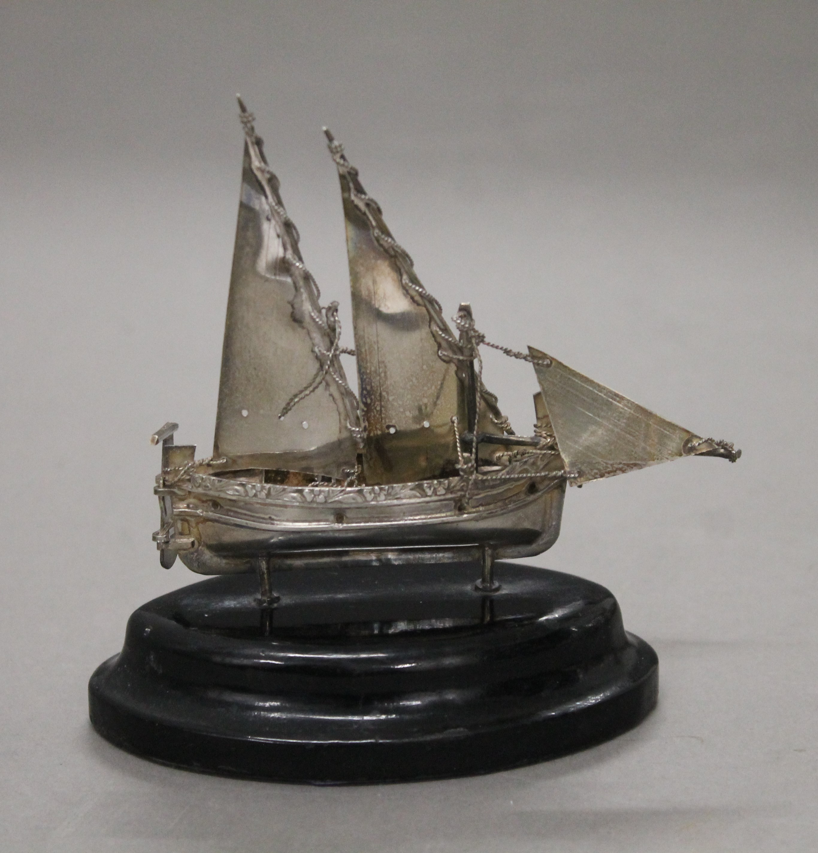 A Maltese silver model of a sailing boat on an oval wooden base. 10 cm high.