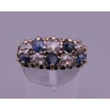 An 18 ct gold diamond and sapphire ring. 8 mm high, 17 mm wide. Ring size Q/R.