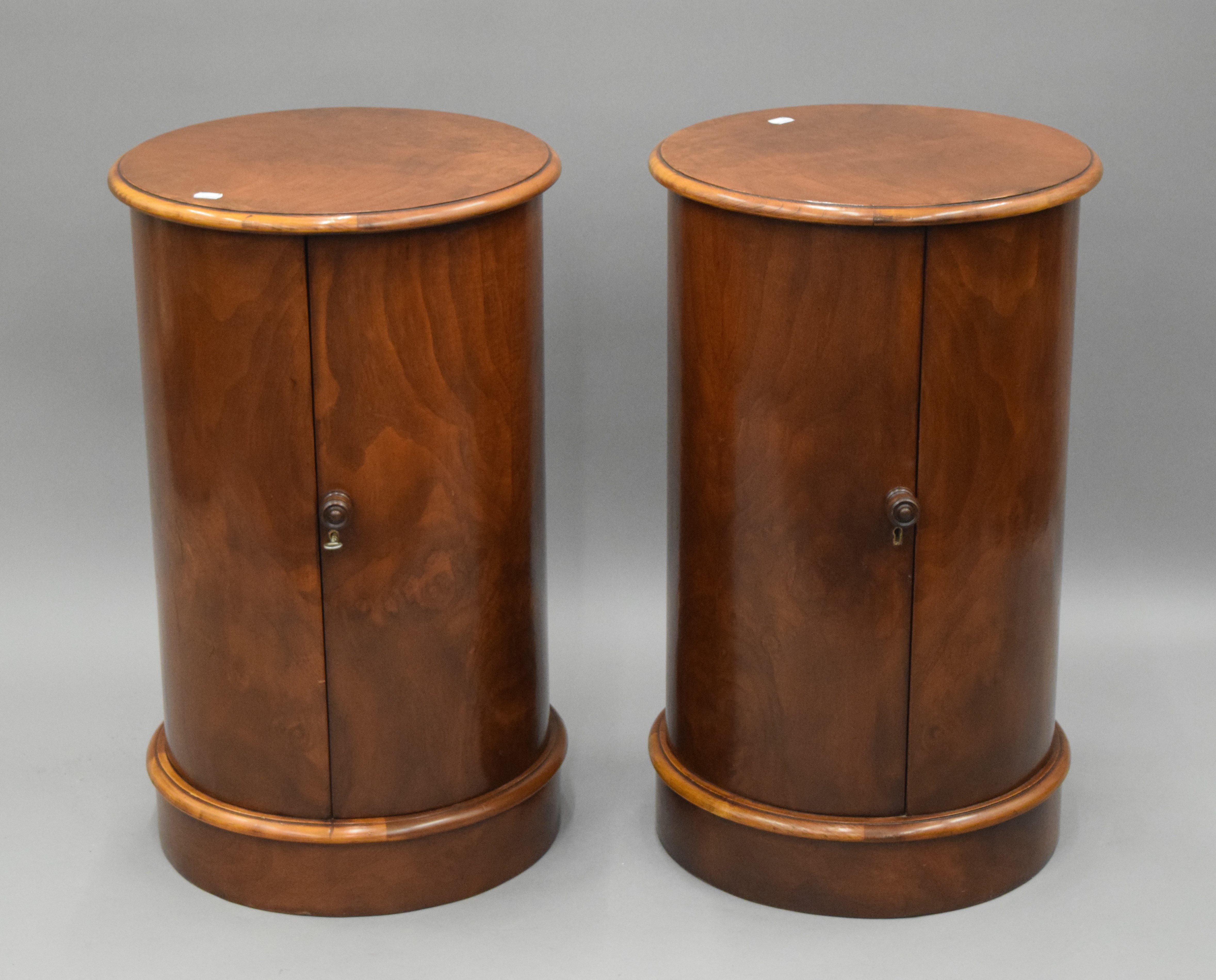 A pair of walnut cylindrical bedside cupboards. 72 cm high x 43 cm diameter.