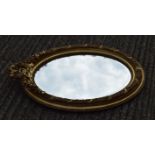 An oval gilt framed mirror. 94 cm high.