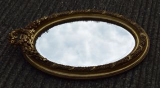 An oval gilt framed mirror. 94 cm high.