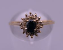 An 18 K gold sapphire and diamond cluster ring. Ring size N/O. 2 grammes total weight.