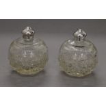 Two round cut glass scent bottles with silver tops, hallmarked Sheffield 1921. 9 cm high.