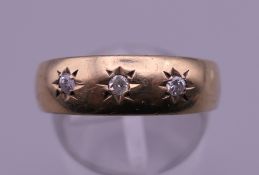 A 9 ct gold three stone diamond gypsy set ring. Ring size Q/R. 2.7 grammes total weight.