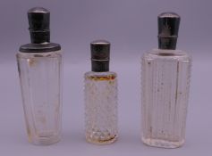 Three silver topped cut glass scent bottles. The largest 9 cm high.