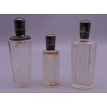 Three silver topped cut glass scent bottles. The largest 9 cm high.