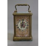 A brass cased carriage clock with painted porcelain panels. 14 cm high.