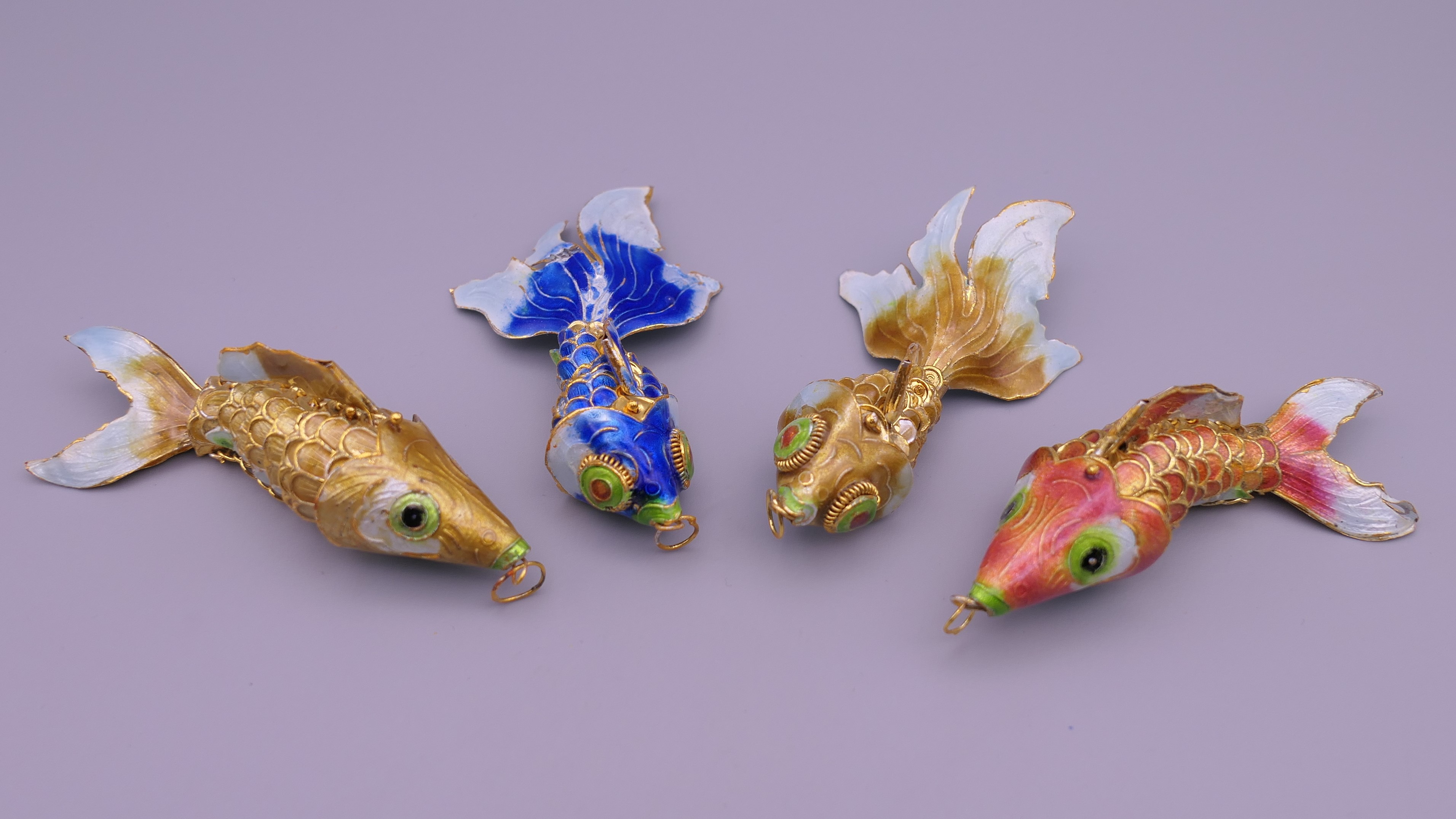 Four enamel decorated fish. The largest 9.5 cm long.