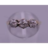 An 18 ct gold three stone diamond ring. Ring size M. 3.1 grammes total weight.