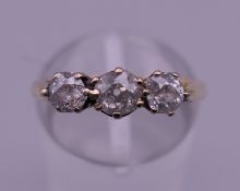 An 18 ct gold three stone diamond ring. Ring size M. 3.1 grammes total weight.