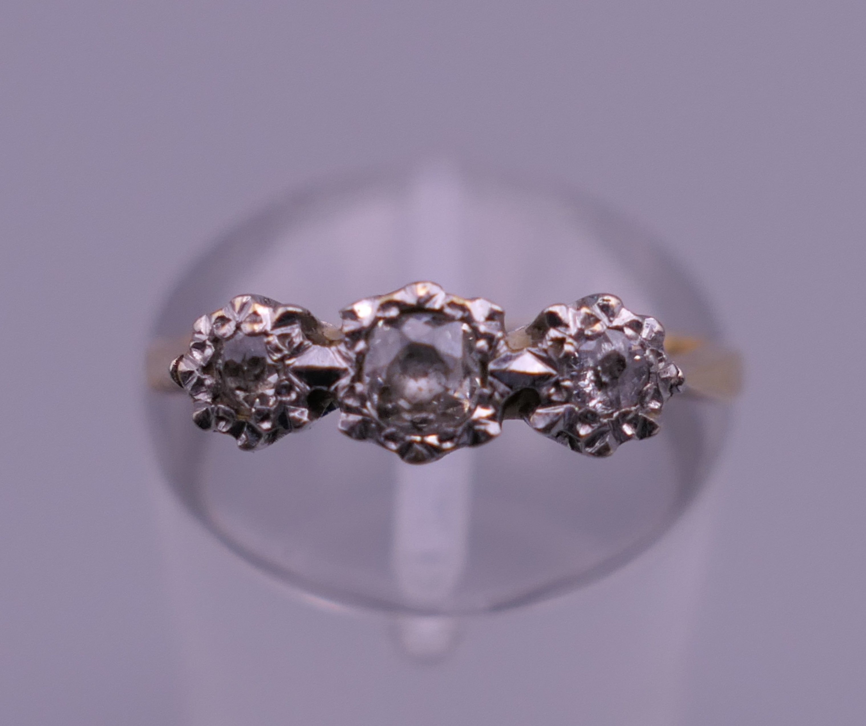 An 18 ct gold and platinum three stone diamond ring. Ring size J/K. 2.3 grammes total weight.