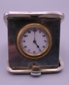 A silver cased travelling clock. 5 cm wide.