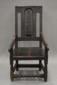 A 17th/18th century oak wainscot elbow chair with carved panelled back. 53 cm wide.