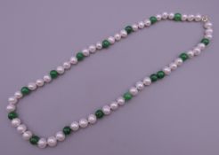 A jade and pearl necklace with a 14 ct gold clasp. 44 cm long.