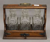 A Victorian oak three bottle tantalus. 36 cm wide.