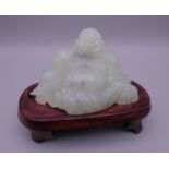 A jade model of Buddha on a wooden stand. 6.5 cm high overall.