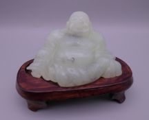 A jade model of Buddha on a wooden stand. 6.5 cm high overall.
