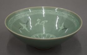 A celadon glaze bowl, the interior decorated with cranes, character marks to base. 15 cm diameter.