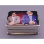 A silver pill box depicting the two Ronnies. 3 cm wide.