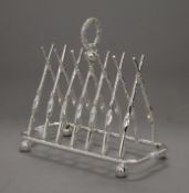 A silver plated toast rack formed as rifles. 19.5 cm long.
