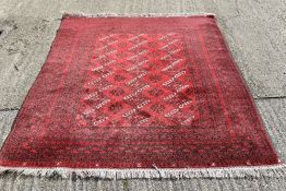 An Afghan red wool rug.