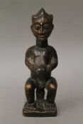 A tribal wooden figure with studded and scarified face. 23 cm high.