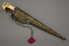 A 19th century Eastern dagger with ivory handle and in impressed brass scabbard. 31 cm long overall.