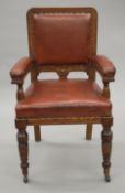 A leather upholstered oak open arm chair. 57 cm wide.
