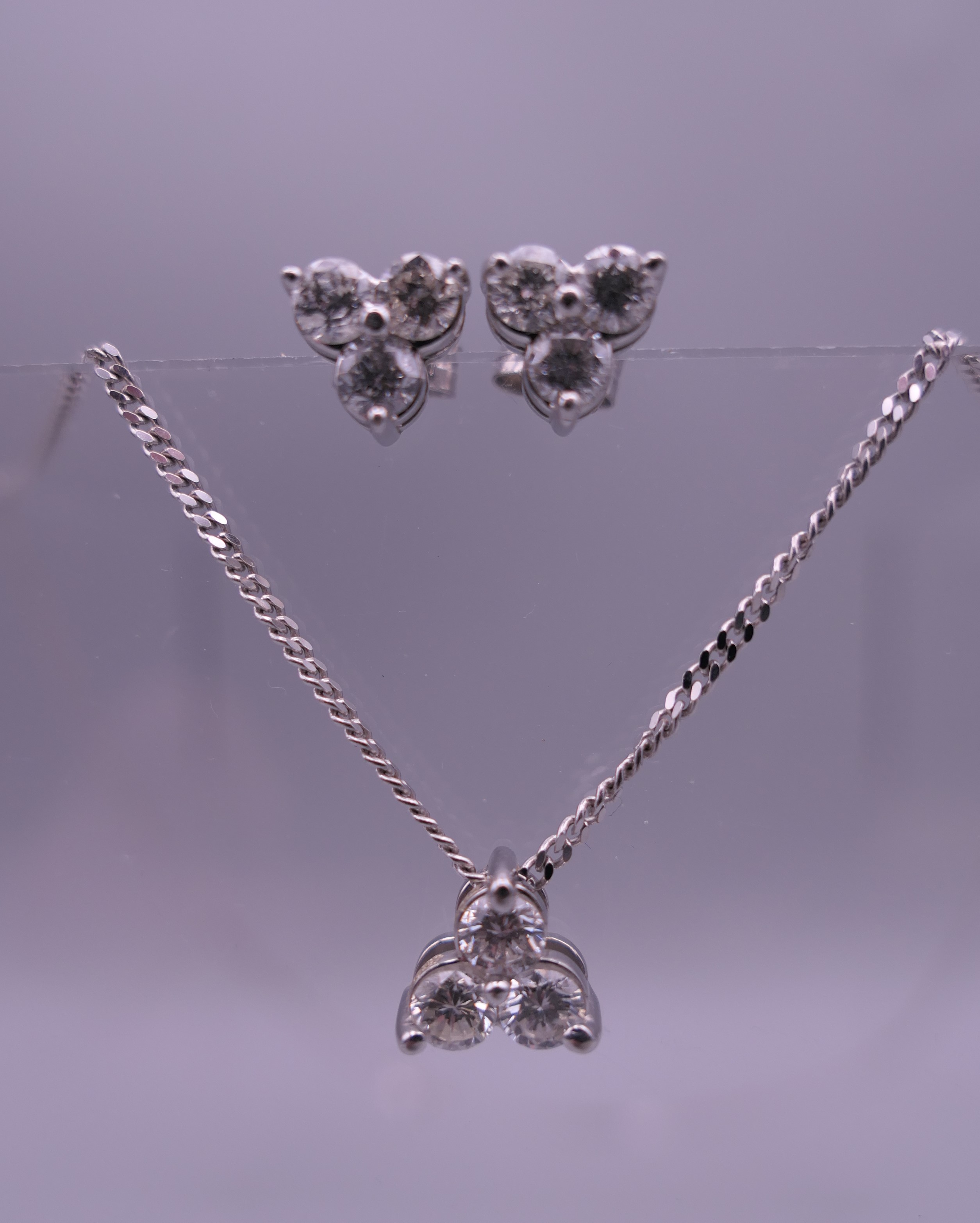 An 18 ct white gold and diamond necklace and pendant and a pair of matching earrings.