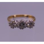 An 18 ct gold three stone diamond ring. Ring size N (with sizing balls). 3.7 grammes total weight.