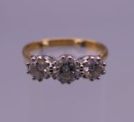 An 18 ct gold three stone diamond ring. Ring size N (with sizing balls). 3.7 grammes total weight.