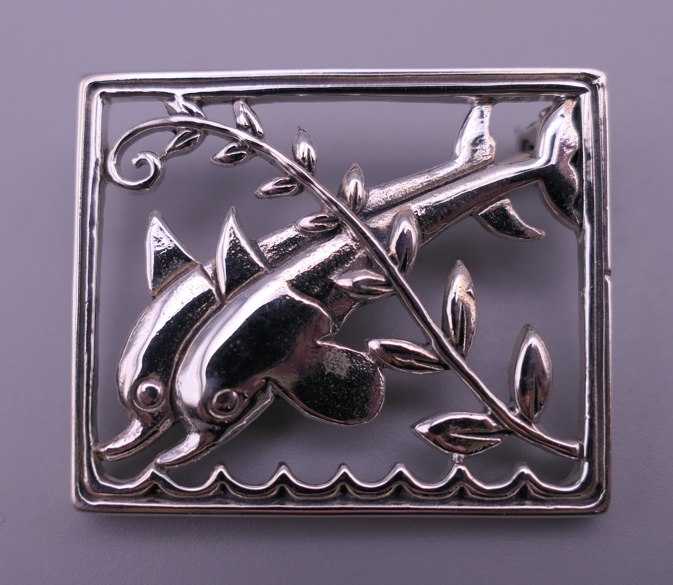 A silver dolphin brooch. 3.5 cm x 2.75 cm.