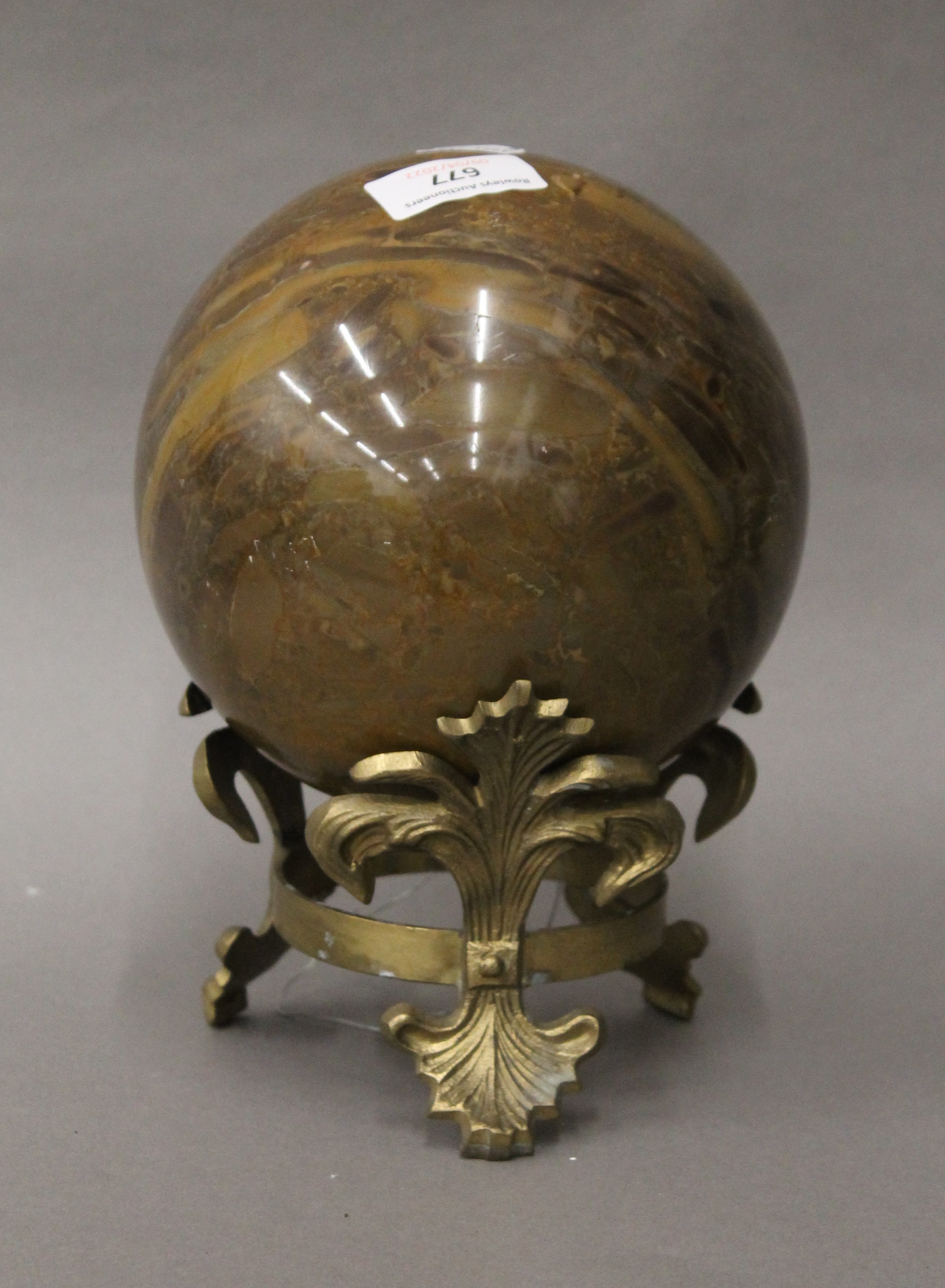 A large marble ball on a brass stand. 20 cm high overall.