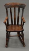 A 19th century elm seated child's splat back rocking chair. 34 cm wide.